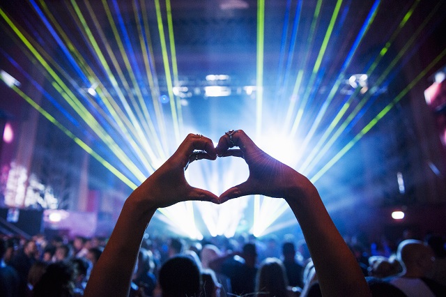 Woman making heart shape with hands at music event